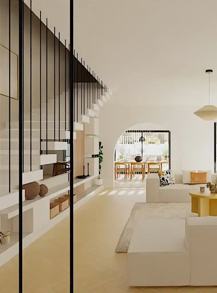 Vue d'un salon avec un escalier design en métal, ouvert sur une salle à manger lumineuse avec une décoration contemporaine.

